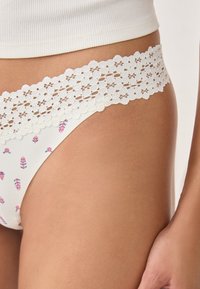 Perizoma bianco con un motivo floreale in rosa e blu, con una ampia finitura in pizzo sulla vita, che mette in risalto una texture delicata.