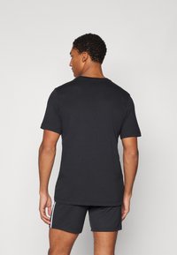 Svart T-skjorte med korte ermer og rund hals, sammen med svarte shorts med hvite sidestriper. Glatt bomullsstruktur.