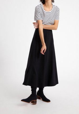 Raidallinen valkoinen ja laivastonsininen T-paita yhdistettynä virtaavaan mustaan maxi-hameeseen. Asusteena on tiukat mustat nilkkurit, joissa on paksu korko.