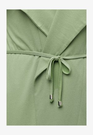 Abito avvolgente in tessuto verde con cintura regolabile e dettagli pendenti in metallo. Texture morbida con una finitura liscia e design stratificato.