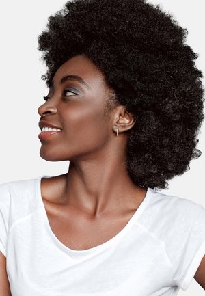 Profil av en person med fylligt svart naturligt hår, iförd en vit T-shirt, som har en liten guldkulörsring och slät hud.