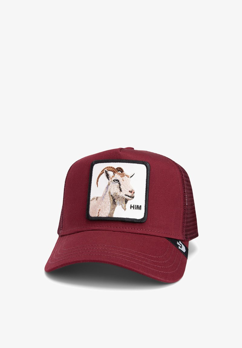 Red baseball cap featuring a square patch with an embroidered goat and the text "HIM." The cap has a solid front and mesh back.