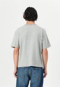 Grå bomulds t-shirt med korte ærmer, rund hals og en afslappet pasform. Ryggen har et enkelt, rent design uden yderligere detaljer.
