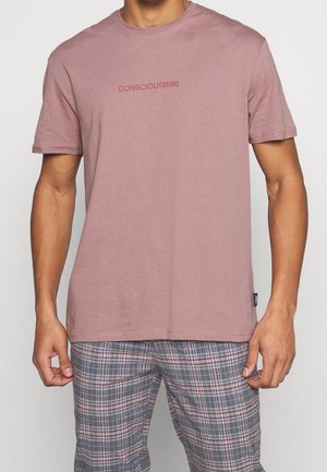 Short-sleeve, crew-neck t-shirt in dusty rose cotton with "CONSCIOUSMIND" printed in a darker hue across the chest. Soft texture.