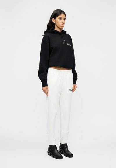 Μαύρο κοντό φούτερ με κεντημένο λογότυπο, σε συνδυασμό με λευκή φόρμα με κορδόνι στη μέση. Μαύρα μποτάκια αστραγάλου ολοκληρώνουν το σύνολο.