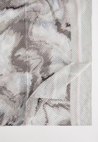 Multicolored textured fabric, featuring a marbled pattern in gray and soft pink, with diagonal stripes and a folded edge.