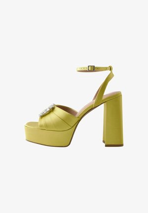 Yellow satin platform sandal with a wide heel, featuring a decorative crystal accent and an adjustable ankle strap. Smooth texture.