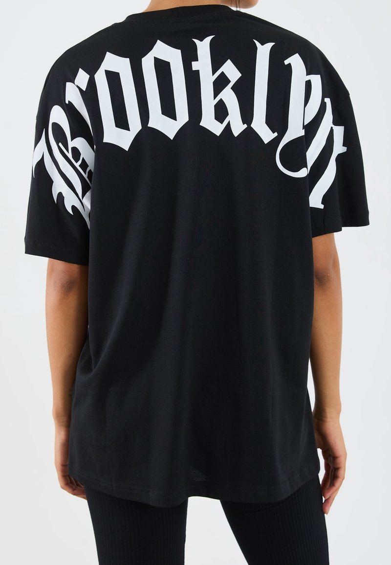 Mustapohjainen ylisuuri t-paita, jossa on selässä suuri valkoinen "Brooklyn" -teksti. Lyhyet hihat, puuvillamateriaali, rento malli.