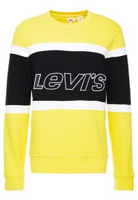 Žlutá a černá mikina s bílými pruhy, se stojatým límcem a logem "Levi's" v černé barvě. Vyrobena z měkké, strukturované tkaniny, s žebrovanými manžetami a lemem.