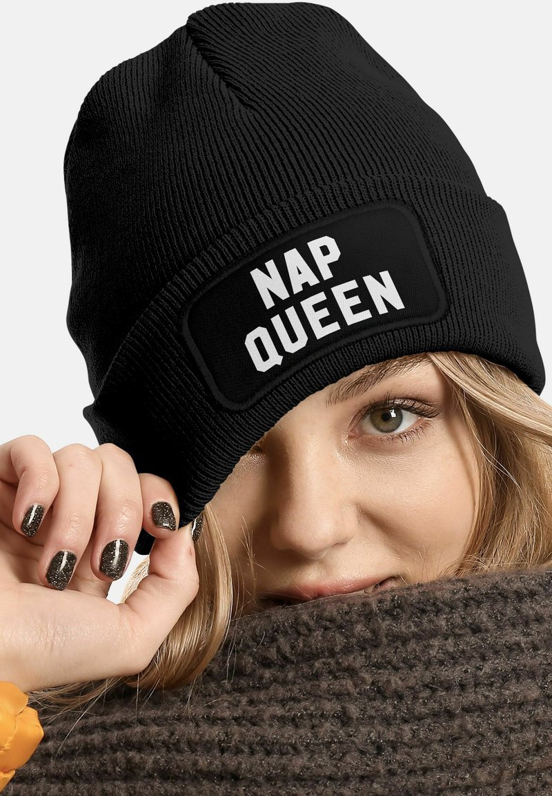 Black knit beanie with a folded cuff displaying the text "NAP QUEEN" in bold white letters. Soft, textured fabric.