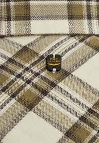 Geruite stof in crème, olijf en bruine tinten. Bevat een visgraatpatroon met een zwart label met de tekst "PME LEGEND" en gele accenten.