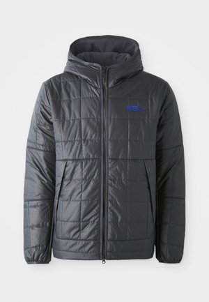 Giacca imbottita grigia con cappuccio, caratterizzata da una texture in tessuto trapuntato, loghi blu "INTER" e Nike, chiusura frontale con zip e tasche laterali.