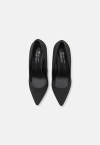 Escarpins noirs à bout pointu avec une finition mate et lisse, dotés d'un design à enfiler et d'un talon légèrement surélevé pour plus de hauteur.