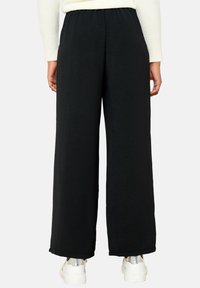 Black wide-leg pants made of textured fabric with an elastic waistband, featuring a relaxed fit and a smooth hem at the ankles.