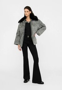 Gray patterned denim jacket with a black fur collar, paired with a black top and flared black pants, featuring a metallic belt buckle.