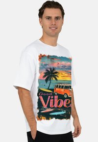 Wit T-shirt met korte mouwen met een kleurrijke retroprint van een busje, palmbomen en surfplanken, met de tekst "Good Vibes".