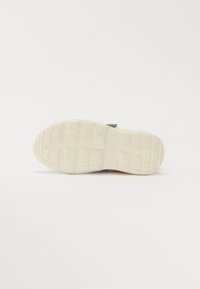 Kopogós teppe fehér gumipohárral, amelynek texturált felülete van, rácsos mintával és enyhén kiemelkedő részekkel a tapadás érdekében. Minimalista dizájn.