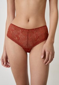 Briefs hipster rossi in pizzo, con motivi floreali, bordi ondulati e un design semi-trasparente. Texture morbida con un taglio a vita alta.