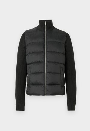 Gilet invernale nero con un alto collo e maniche a maglia. Presenta sezioni trapuntate e una chiusura frontale con cerniera. Tessuto complessivamente liscio.
