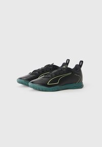 Scarpe da ginnastica nere con una tomaia sintetica testurizzata, accentuate da dettagli in verde neon e una suola in gomma verde, progettate per supporto e aderenza.