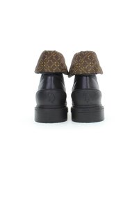 Scarpe in pelle nera con un gambale superiore a motivo marrone e dettagli dorati. Suola spessa e testurizzata per una maggiore durabilità. Logo discreto sul tallone.