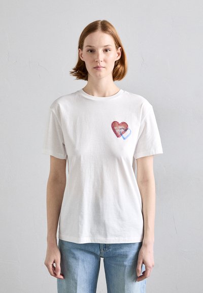 T-shirt en coton blanc avec un motif de cœur rouge et des accents bleus sur la poitrine gauche, col rond standard et manches courtes.
