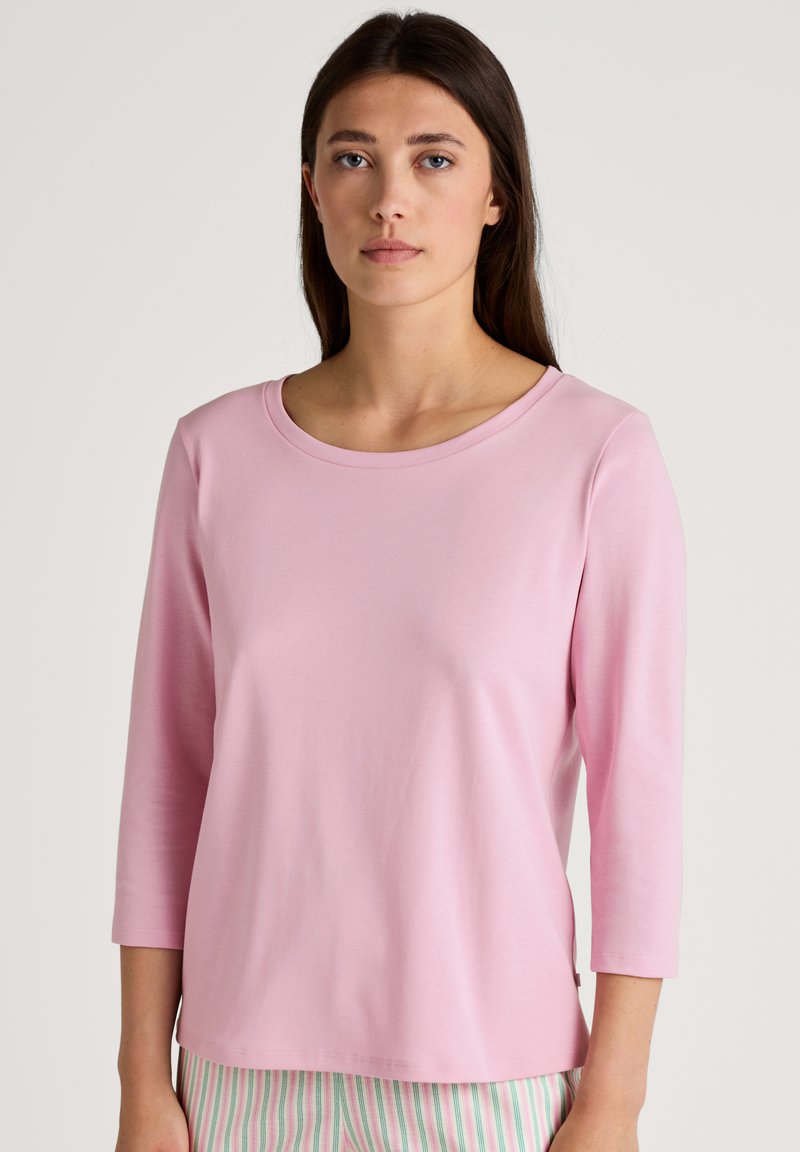 Lichtroze longsleeve top met een ronde halslijn, een gladde textuur en een relaxte pasvorm. Het kledingstuk loopt tot aan de taille en wordt gecombineerd met gestreepte broek.