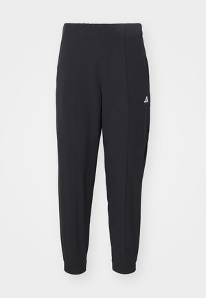 Black athletic pants made from a smooth fabric. Tapered design with elastic cuffs. Features a small white logo on the left hip.
