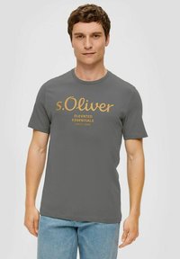 Gray short-sleeve t-shirt with a round neckline, featuring a gold printed logo and text on the front. Material appears smooth and lightweight.