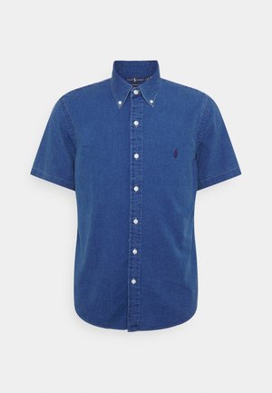 Blauw denim overhemd met korte mouwen, knoopsluiting, kraag en een klein logo geborduurd op de linkerborst.