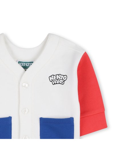 Camicia bianca con bottoni, maniche corte rosse, due tasche frontali blu e logo "Kenzo Paris" sul petto.