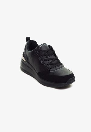 Sneaker nera con una finitura in pelle liscia e texture perforata. Presenta un colletto imbottito, chiusura con lacci e un accento metallico sul tallone.