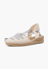 Sandale compensée en toile beige avec des accents en ruban gris et une semelle en jute tressé. Elle dispose d'un dos ouvert et de brides croisées sur les orteils.