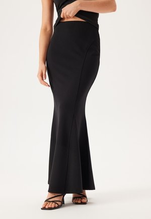 Zwarte, aangesloten maxi rok met een uitlopende onderkant, gemaakt van een soepel materiaal. Heeft naaddetails en een hoge tailleband. Draag het met sandalen met bandjes.