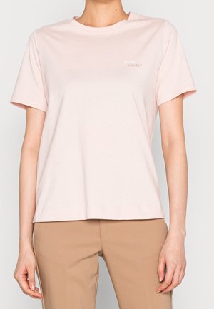 T-shirt en coton rose clair, manches courtes, col rond, avec un texte subtil "Hello Lovely" dans le coin supérieur gauche.
