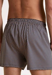 Zomer zwembroek voor heren in een blauw en beige geometrisch patroon, met een elastische tailleband en zachte, lichte stof.