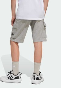 Gray cargo shorts with patch pockets, featuring an Adidas logo in black. Paired with black and white athletic shoes and light-colored socks.