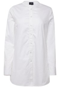 Camicia bianca con bottoni, maniche lunghe, colletto rotondo, pattina frontale e una leggera lucentezza. Presenta un orlo dritto e spacchi laterali per facilitare i movimenti.