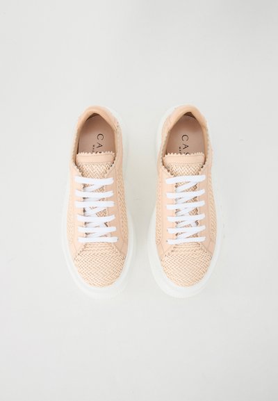Peach-colored sneakers with woven texture, white flat laces, and a white rubber sole. Minimalist design, no visible logos.
