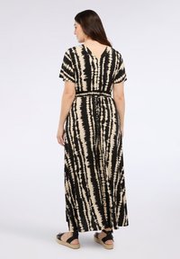 Vestido maxi de tie-dye en negro y beige con mangas cortas, espalda en V y cintura ceñida; cuenta con una falda fluida y una silueta relajada.