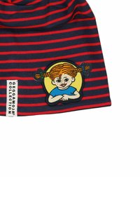 Raidallinen sininen ja punainen pipo, jossa on broderattu merkki, jossa on pigtailleihin sidottu tyttö, jolla on pisamia, hymyilemässä keltaista ympyrää vasten.
