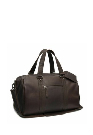 Donkerbruine leren reistas met dubbele handvatten, voorvak met rits en afneembare schouderriem, staand op witte achtergrond.