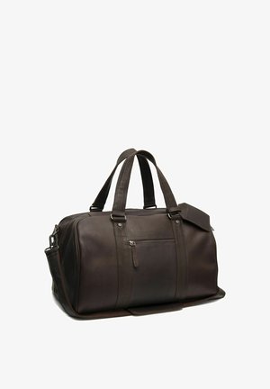 Donkerbruine leren reistas met dubbele handvatten, voorvak met rits en afneembare schouderriem, staand op witte achtergrond.