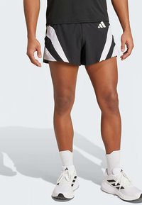 Calções pretos com riscas angulares brancas, feitos de tecido leve. Apresentam um cós elástico e um pequeno logótipo perto do cós.