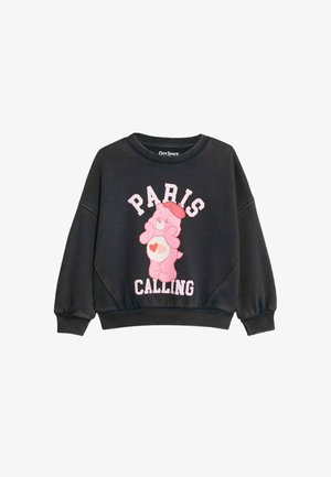 Zwarte sweatshirt met ronde hals, voorzien van een roze Care Bear graphic en de tekst "PARIS CALLING" in wit en roze. Geribbelde manchetten en onderrand.