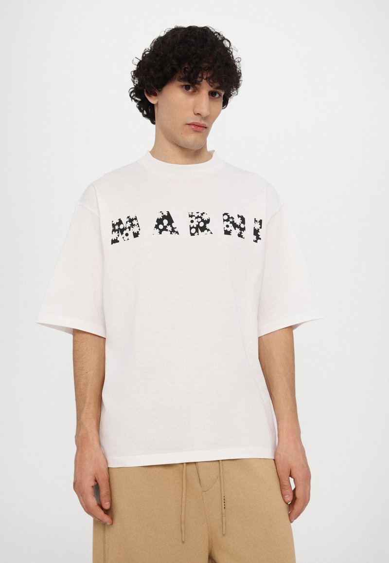 Weißes Baumwoll-T-Shirt mit lockerer Passform, das ein schwarzes Blumenmuster in den Buchstaben mit der Aufschrift "MARNI" zeigt. Kurze Ärmel und runder Halsausschnitt.