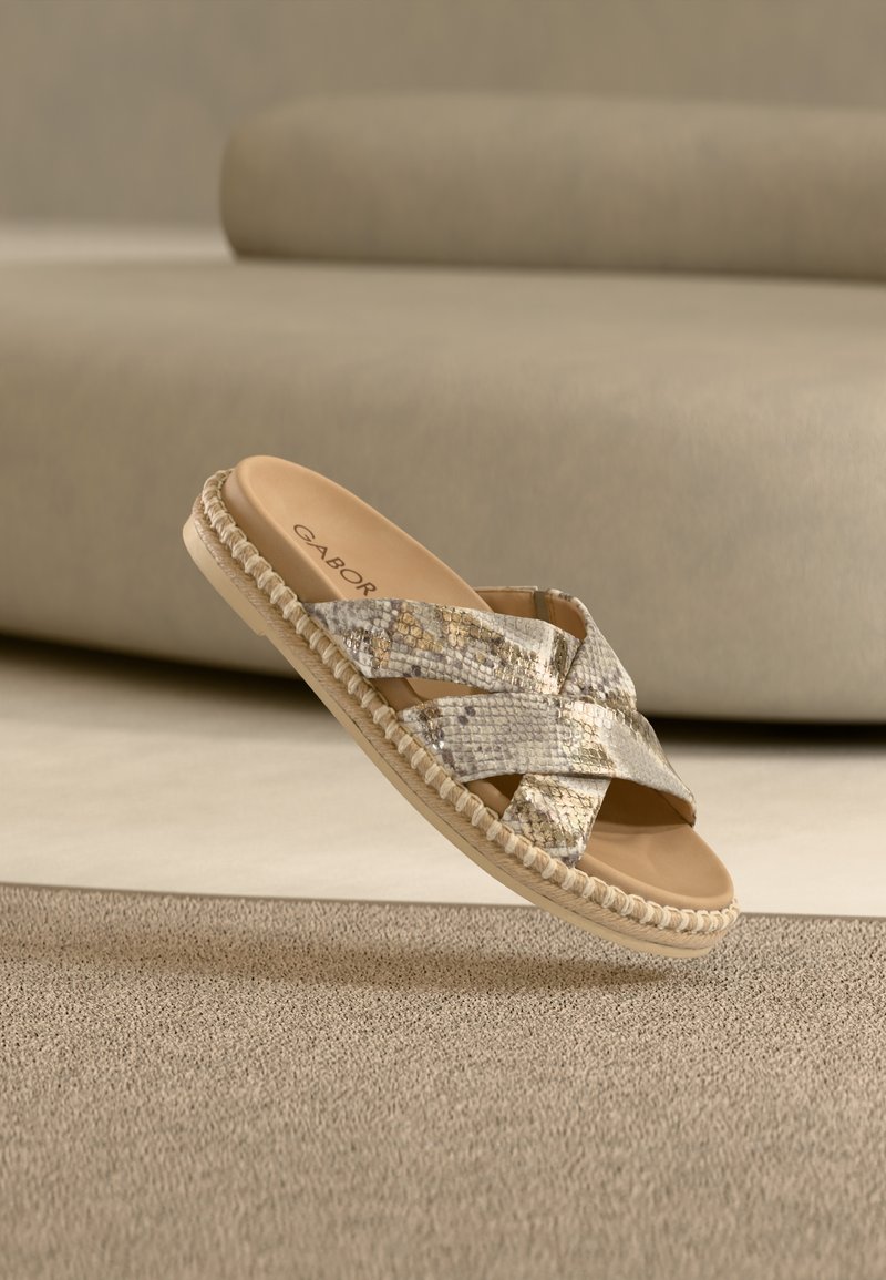 Sandale plate à enfiler beige et or avec des brides croisées, en matière synthétique texturée, semelle plate et semelle intérieure rembourrée. Logo de la marque à l'intérieur.