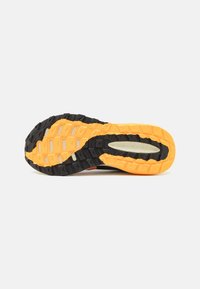 Suela de banda negra y naranja con patrón en zigzag; goma texturizada para mayor agarre; acentos naranjas en secciones negras; diseño ligero.