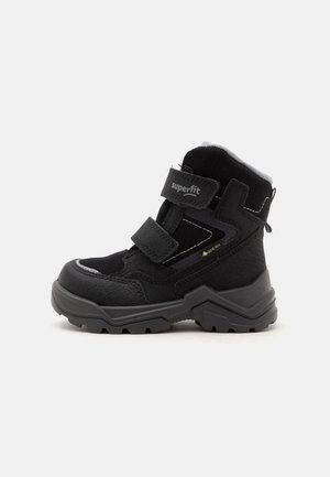 Čierna detská zimná čižma s suchými zipsami, hrubou robustnou podrážkou, štítkom Gore-Tex a značkou "superfit" na hornej páske.