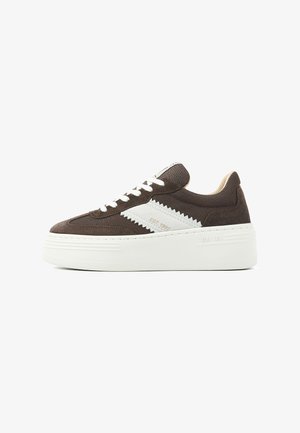 Braune Wildleder- und Stoff-Sneaker mit weißem Zickzackakzent, flacher weißer Plattformsohle und Schnürverschluss. Strukturierte Oberfläche und minimalistische Markenkennzeichnung.